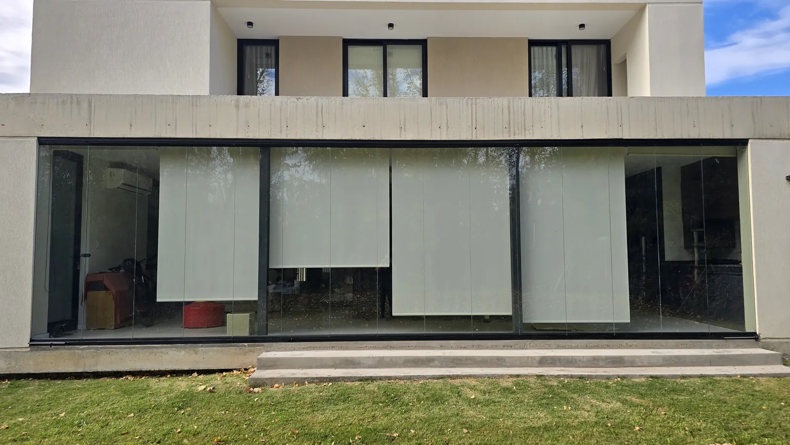 Frente de vivienda con cortina de cristal de 12 metros abierta al parque - obra de JN Aluminio en Neuquén