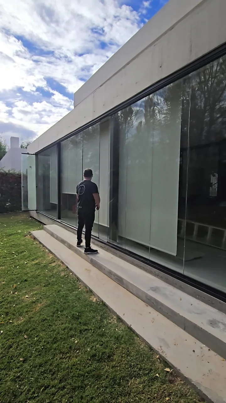 Cerramiento de cristal templado corrido sin perfiles verticales en vivienda de hormigón visto - JN Aluminio Neuquén