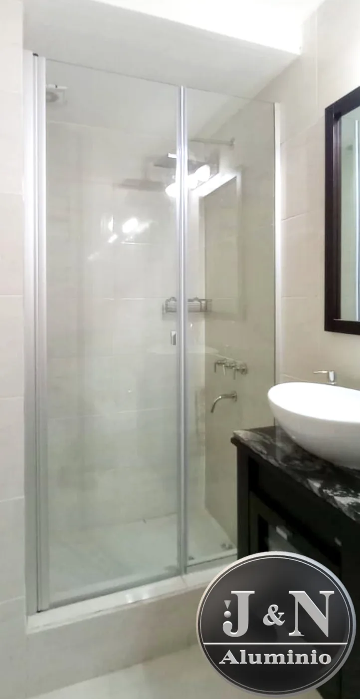 Mampara batiente de vidrio templado en baño moderno con mesada de mármol - JN Aluminio Neuquén