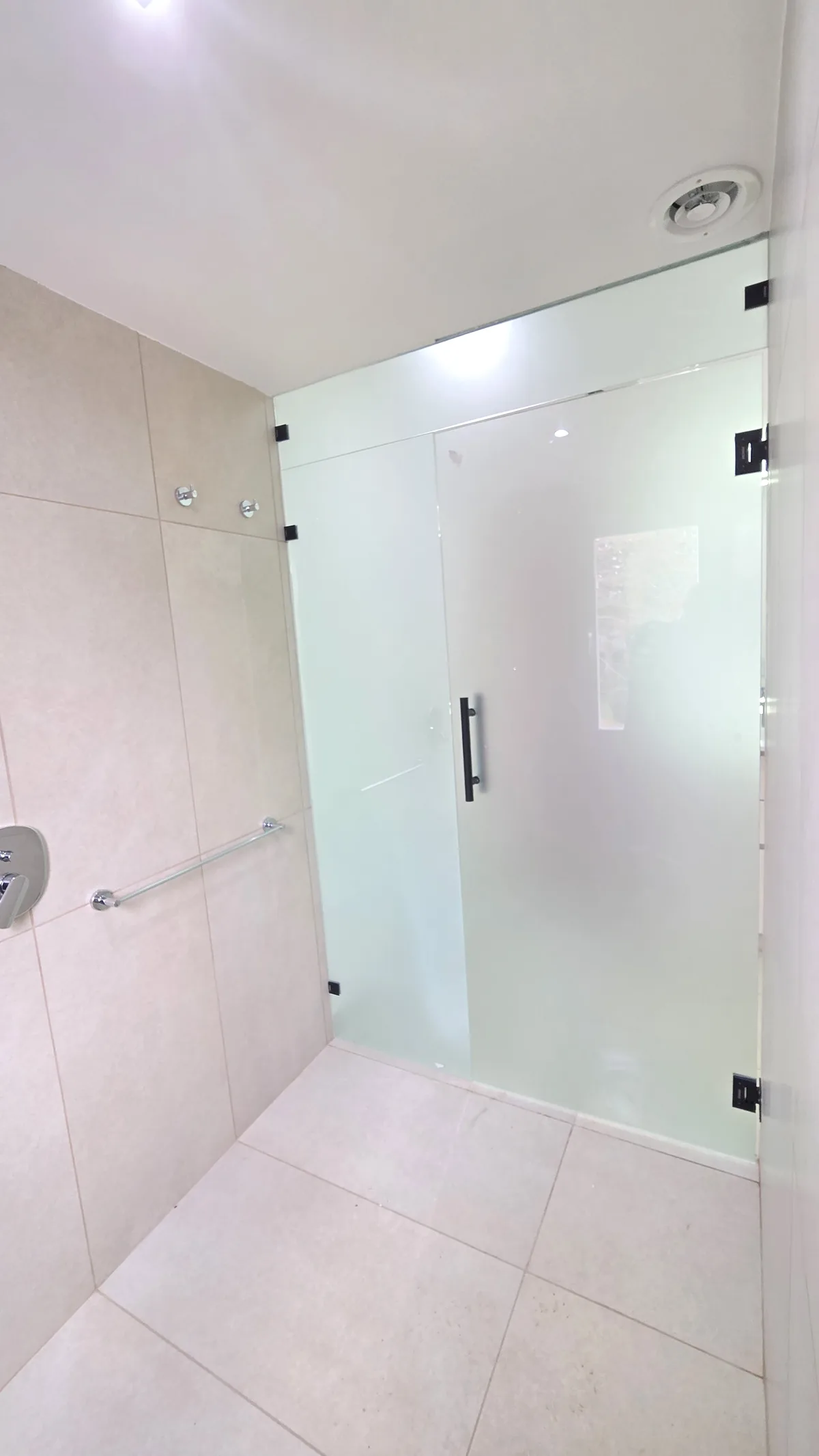 Mampara rebatible de vidrio satinado con manija barral negra instalada en baño de Neuquén - JN Aluminio
