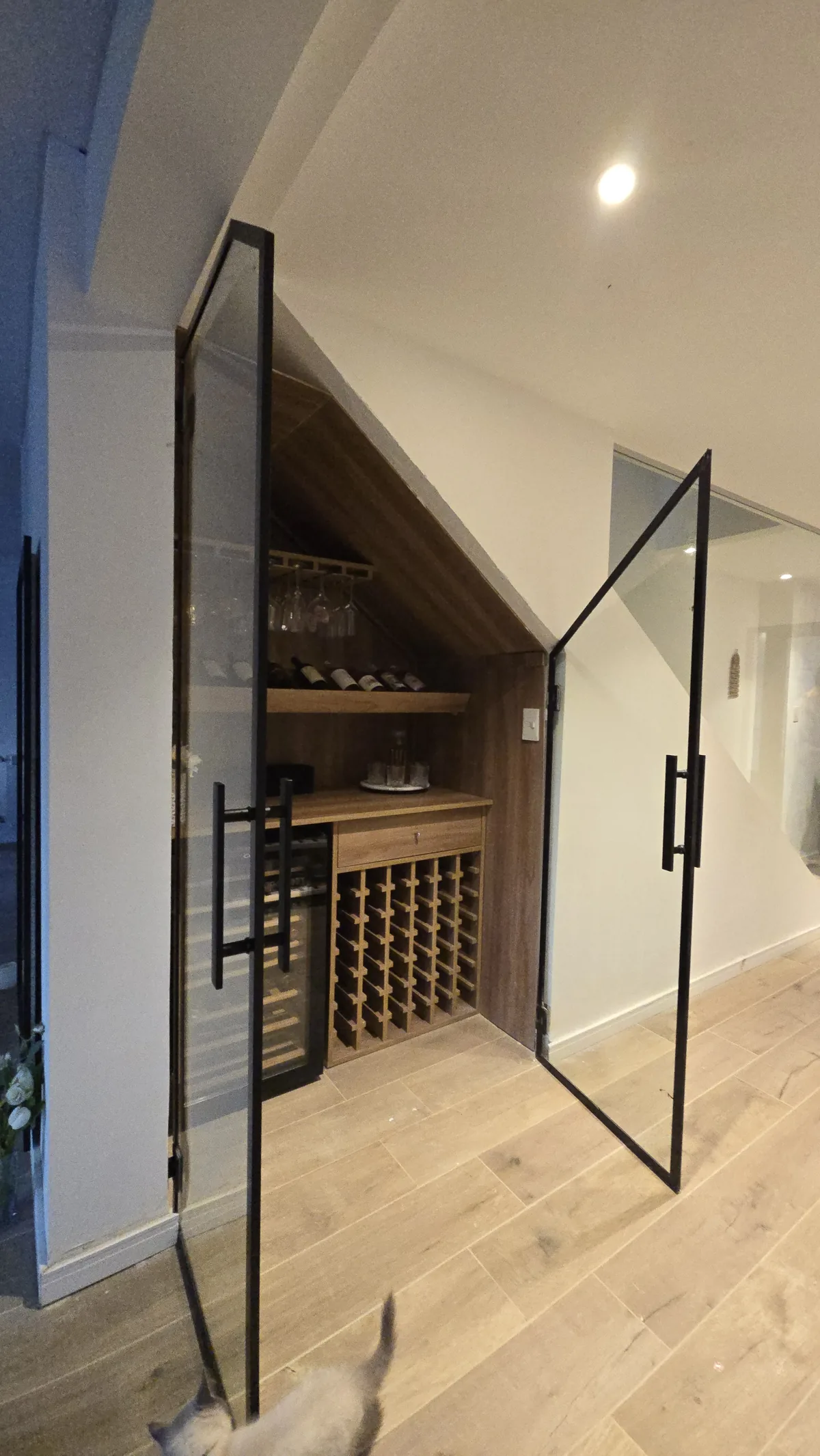 Cava de vino bajo escalera cerrada con puerta de vidrio templado y perfilería negra - obra de JN Aluminio en Neuquén