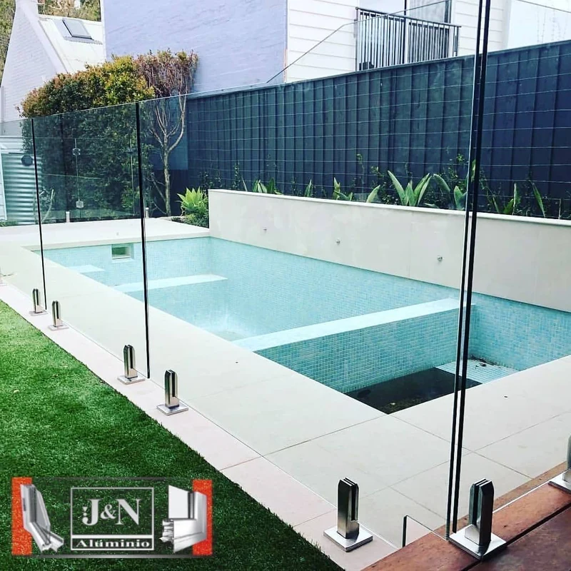 Baranda de vidrio templado con herrajes de acero inoxidable alrededor de pileta - obra de JN Aluminio en Neuquén
