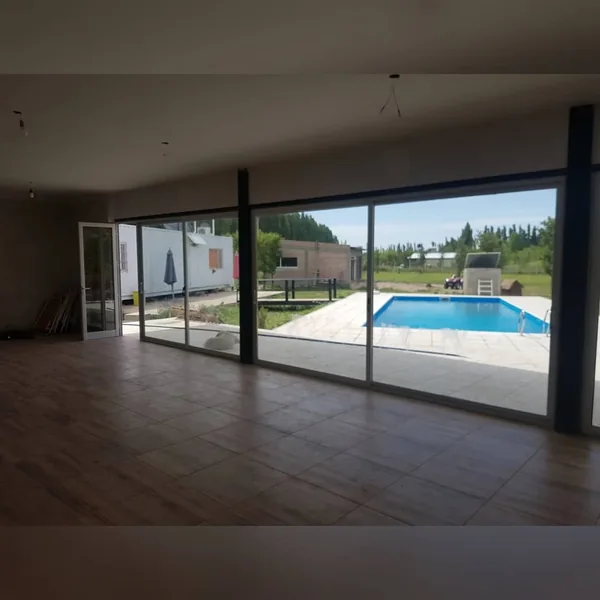 Ventanal corredizo de aluminio de piso a techo abierto hacia la pileta - obra de JN Aluminio en Neuquén
