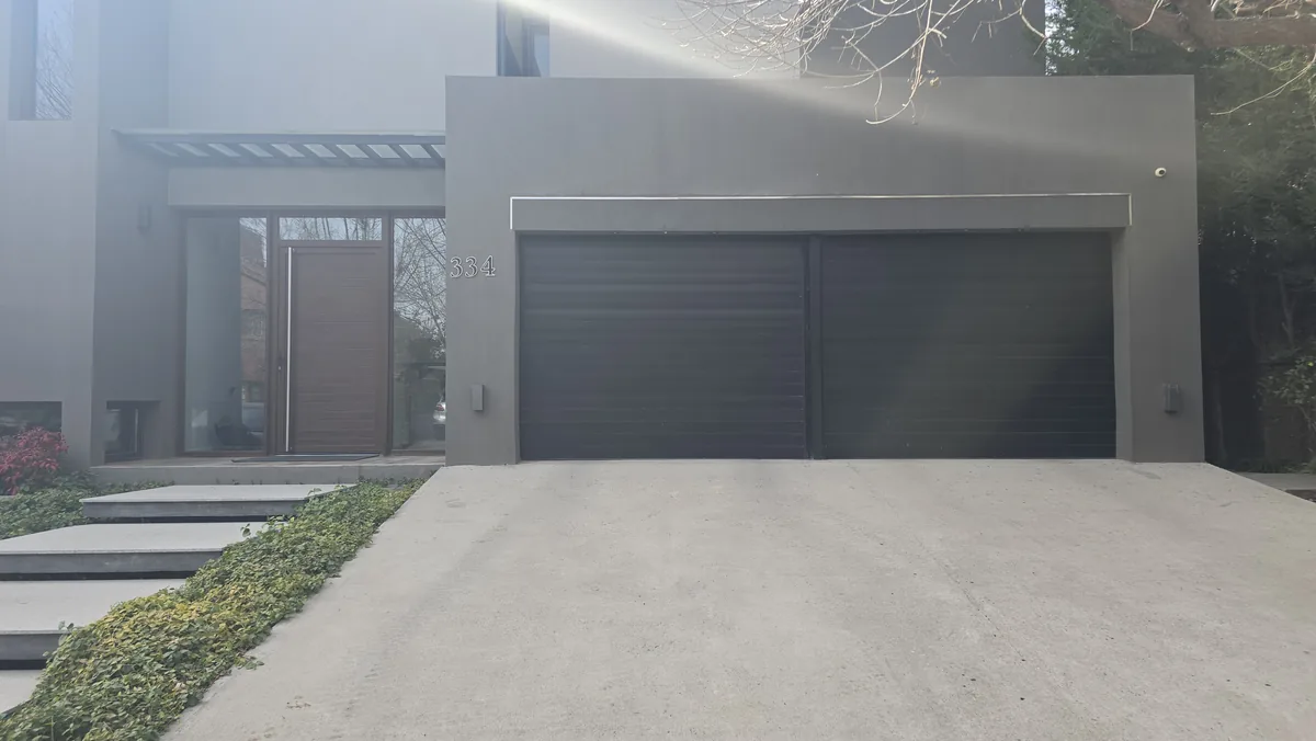 Portón enrollable doble en vivienda moderna con camino de acceso - obra de JN Aluminio en Neuquén