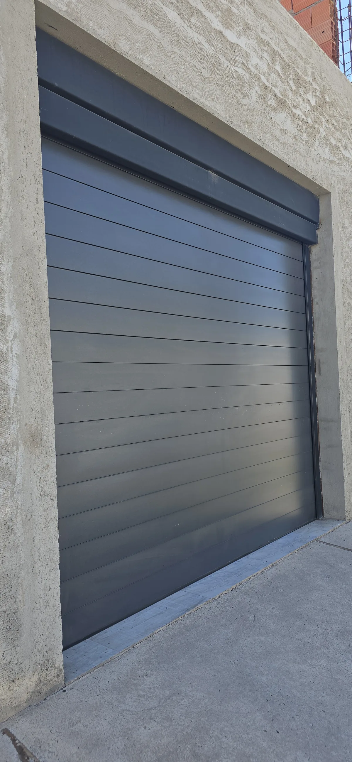 Portón enrollable de aluminio en color negro instalado en el frente de una vivienda - JN Aluminio Neuquén