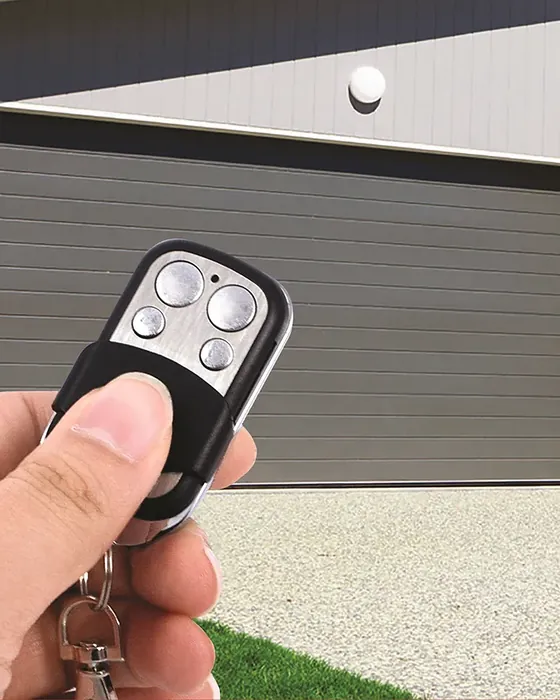 Portón automático enrollable Modelo 125 en una casa moderna, con el control remoto en la mano - J&N Aluminio Neuquén